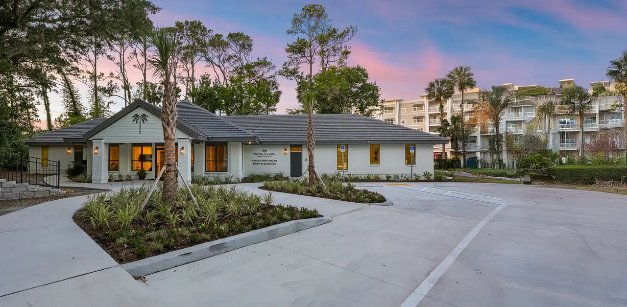 The Ponte Vedra Family Dentistry building at 7000 Sawgrass Village Circle at dusk, with the names of Dr. Perry and Dr. De Bonis on the wall.
